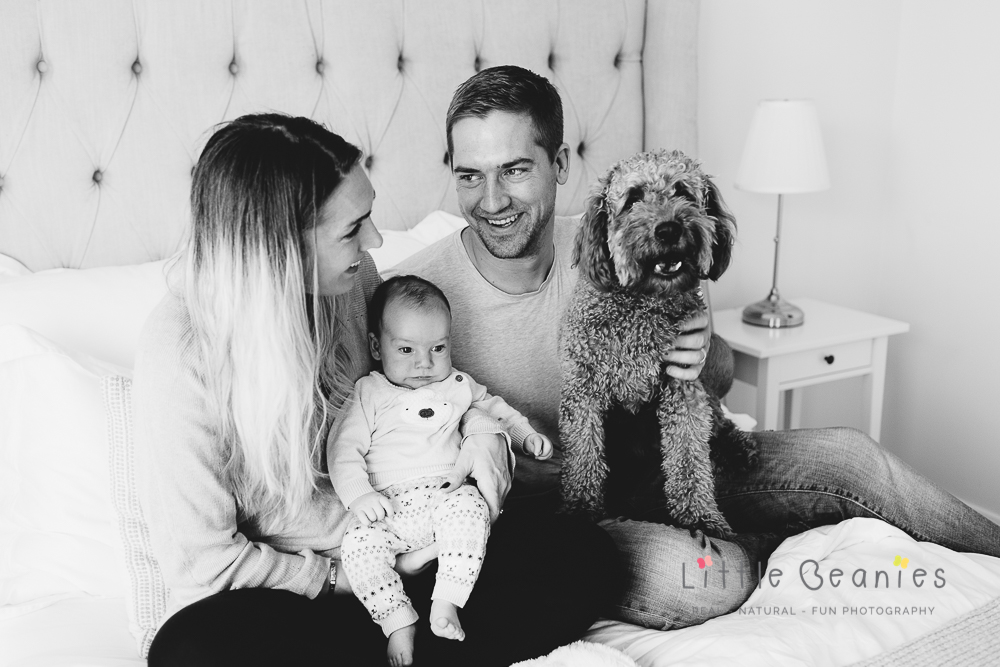 family on bed with dog and newborn baby boy