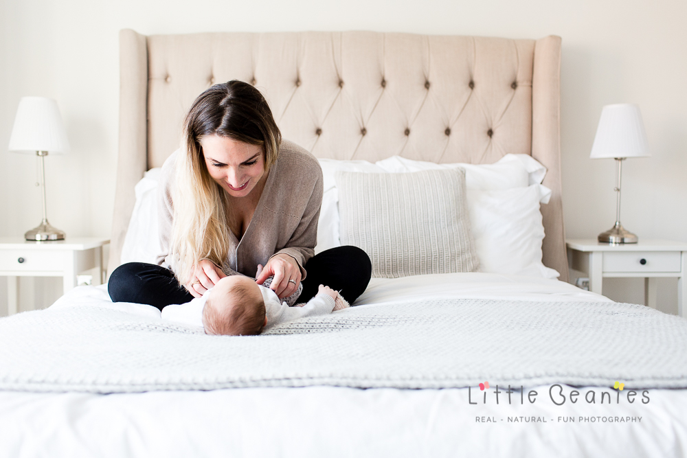mum and baby on king size bed having a giggle on newborn photoshoot