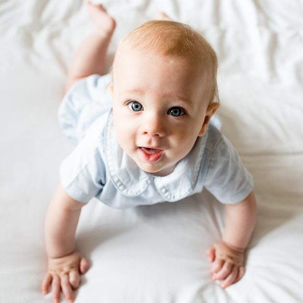 9 month old boy with blue eyes smiling at camera